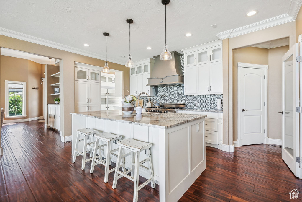 Kitchen featuring white cabinetry, custom range hood, tasteful backsplash, dark hardwood / wood-style flooring, and decorative light fixtures