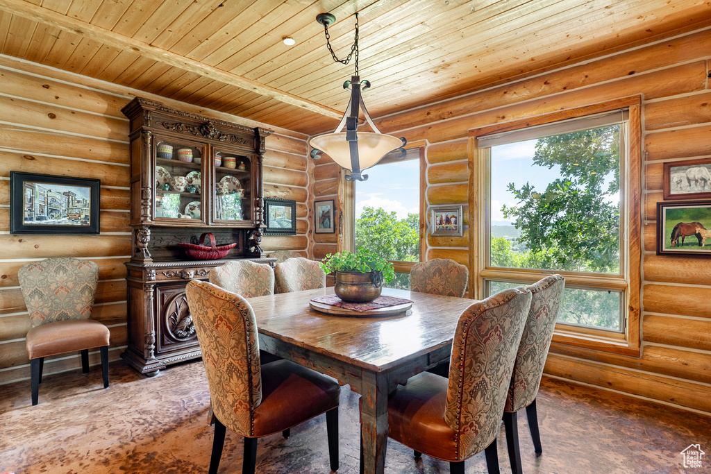 Dining room featuring log walls, a wealth of natural light, and wood ceiling