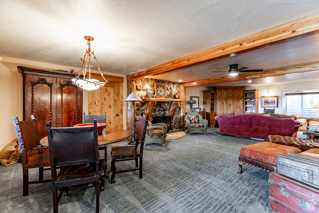 Carpeted dining room with beam ceiling, wooden walls, ceiling fan, and a textured ceiling