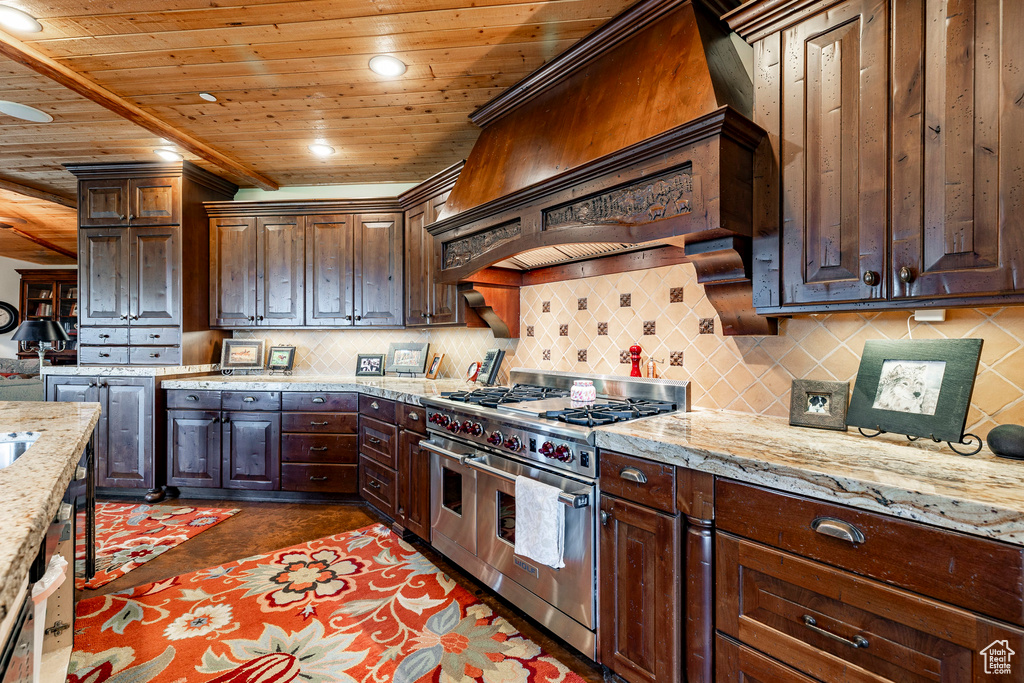 Kitchen featuring range with two ovens, backsplash, wooden ceiling, light stone countertops, and dark brown cabinets