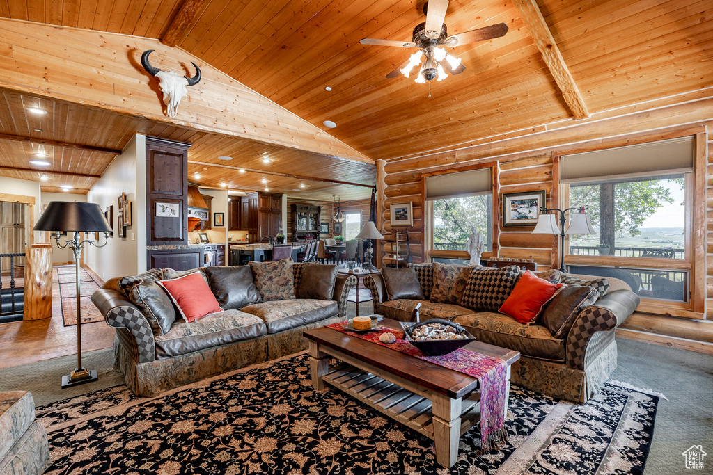 Carpeted living room featuring beamed ceiling, log walls, high vaulted ceiling, wood ceiling, and ceiling fan