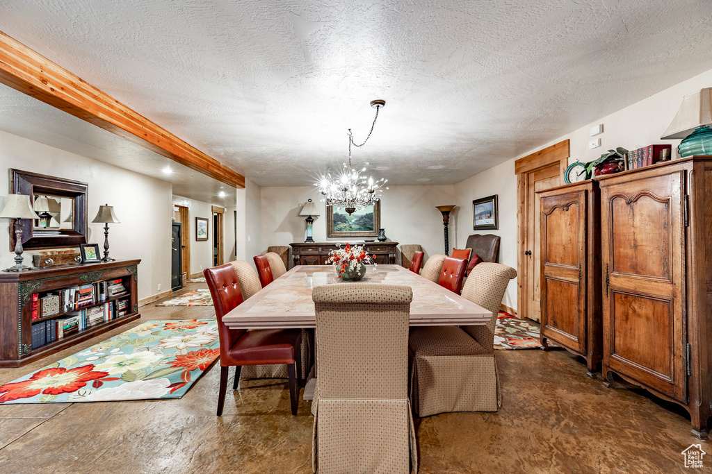 Dining area featuring concrete flooring, a textured ceiling, and an inviting chandelier