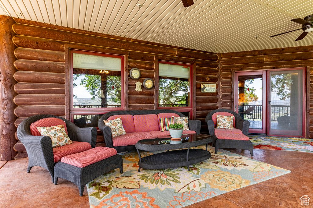 Living room with plenty of natural light, ceiling fan, rustic walls, and wood ceiling