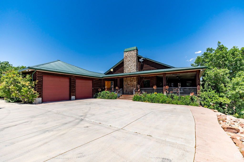 Log cabin featuring a garage and covered porch