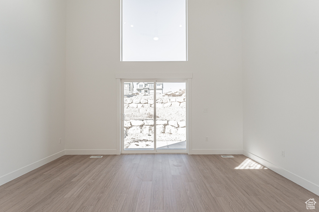 Spare room featuring a towering ceiling and light wood-type flooring