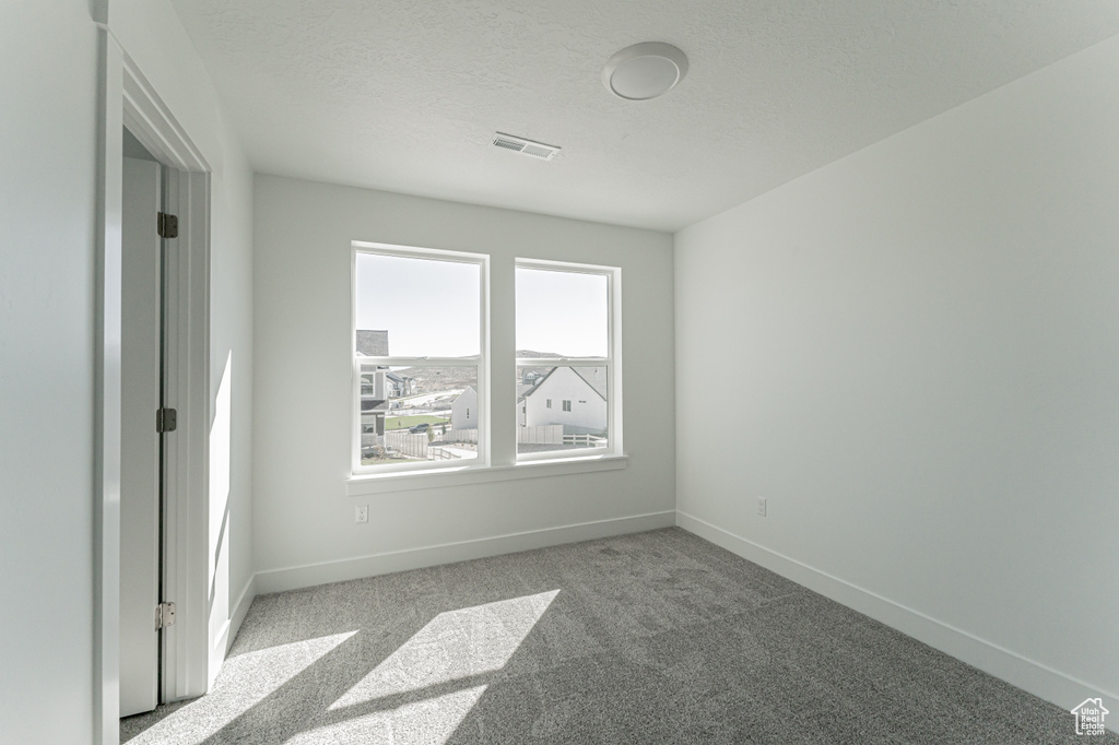 Empty room with a textured ceiling and light colored carpet