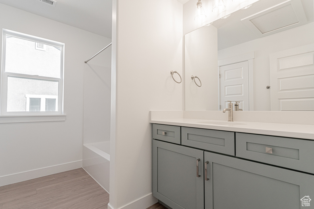 Bathroom featuring vanity, shower / tub combination, and wood-type flooring