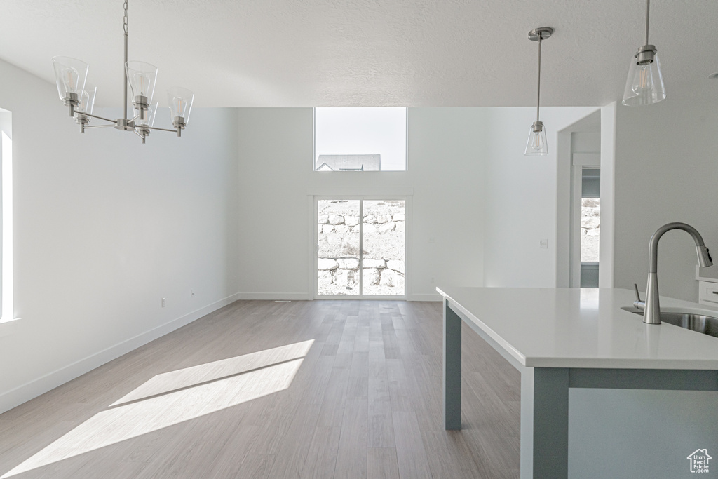 Kitchen featuring sink, a textured ceiling, decorative light fixtures, and light wood-type flooring