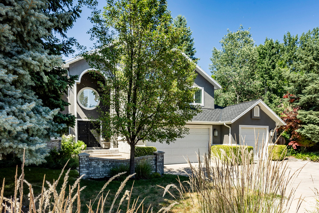 View of property hidden behind natural elements featuring a garage