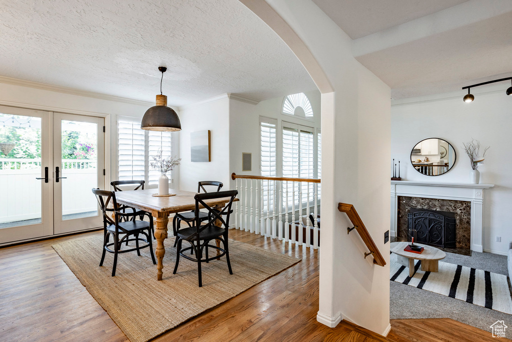 Dining area featuring a fireplace, french doors, a textured ceiling, and light wood-type flooring