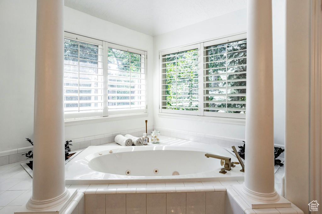 Bathroom featuring ornate columns and tiled tub