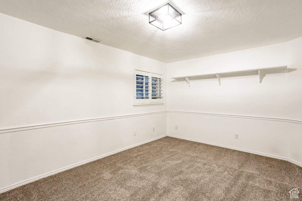 Carpeted empty room featuring a textured ceiling