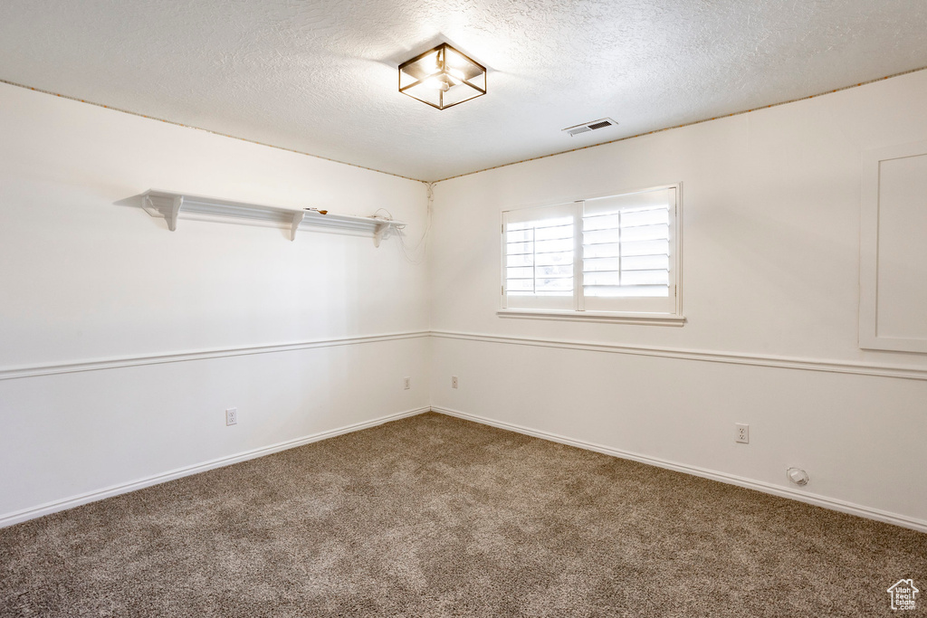 Carpeted empty room featuring a textured ceiling