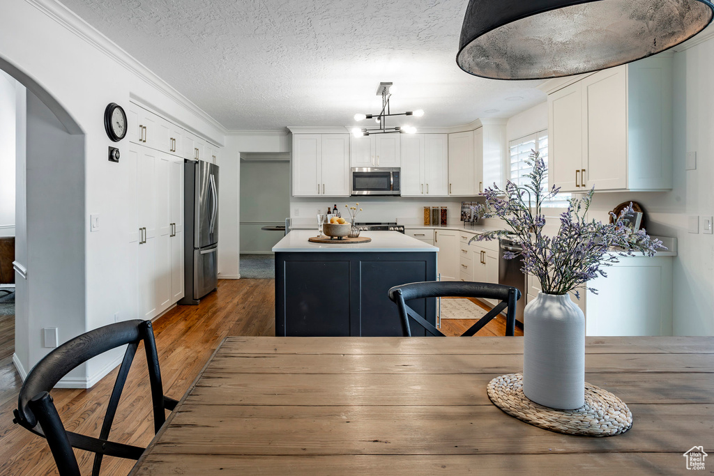 Kitchen featuring stainless steel appliances, white cabinets, a center island, and hardwood / wood-style flooring