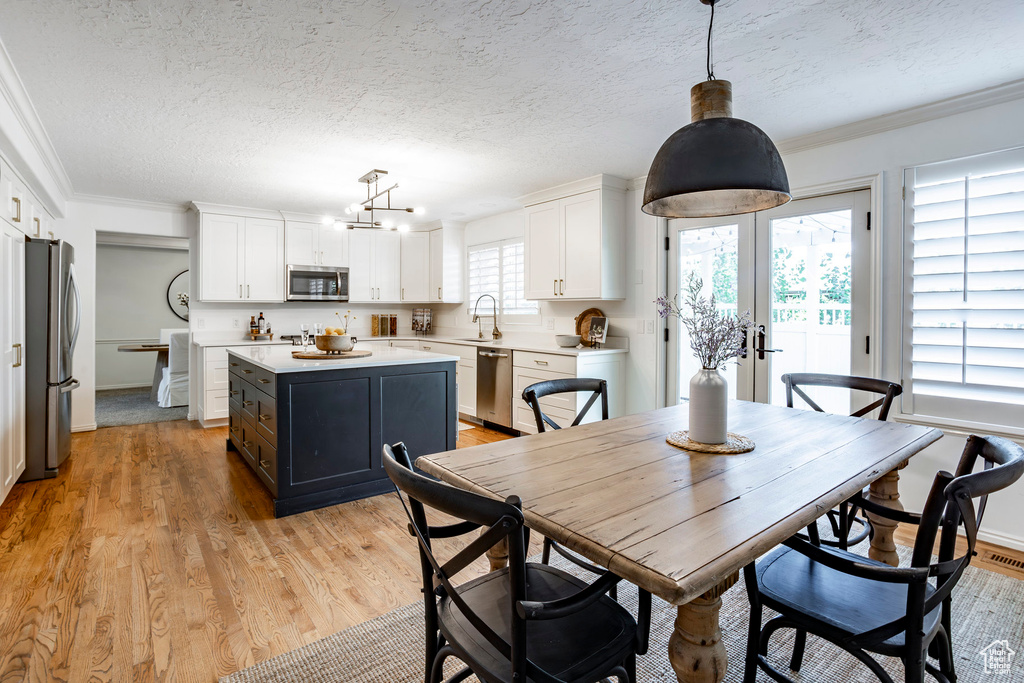 Dining space with light hardwood / wood-style flooring, french doors, a textured ceiling, sink, and ornamental molding