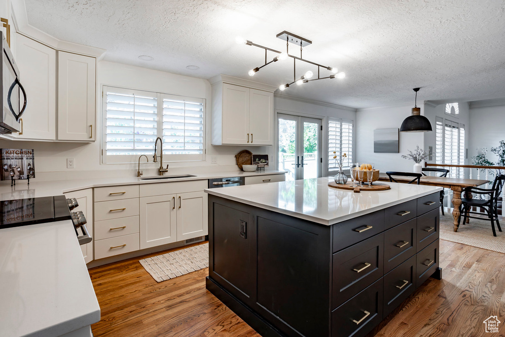 Kitchen featuring hanging light fixtures, sink, a kitchen island, and wood-type flooring