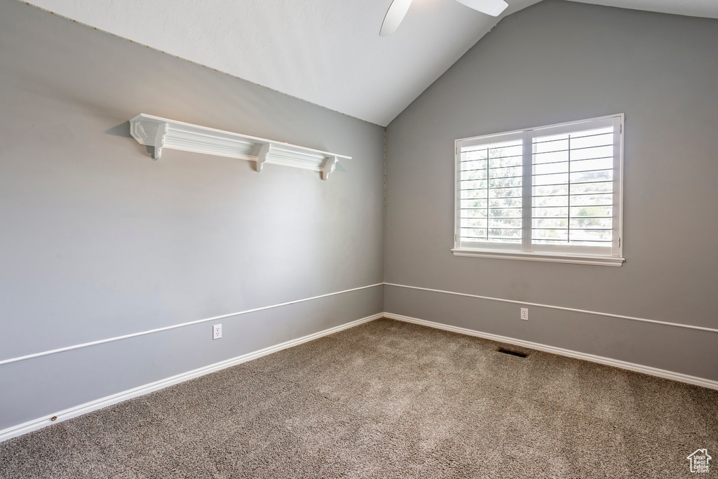 Carpeted empty room with vaulted ceiling and ceiling fan