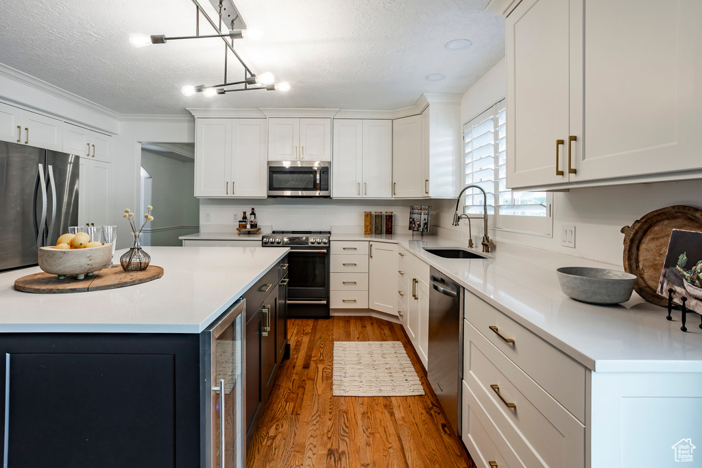 Kitchen with a center island, stainless steel appliances, hardwood / wood-style floors, and white cabinetry