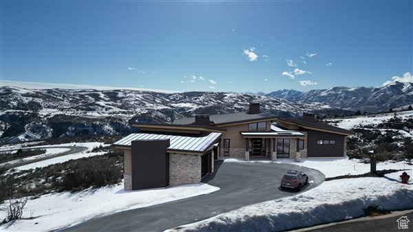 View of front of property with metal roof, stone siding, a standing seam roof, and a garage