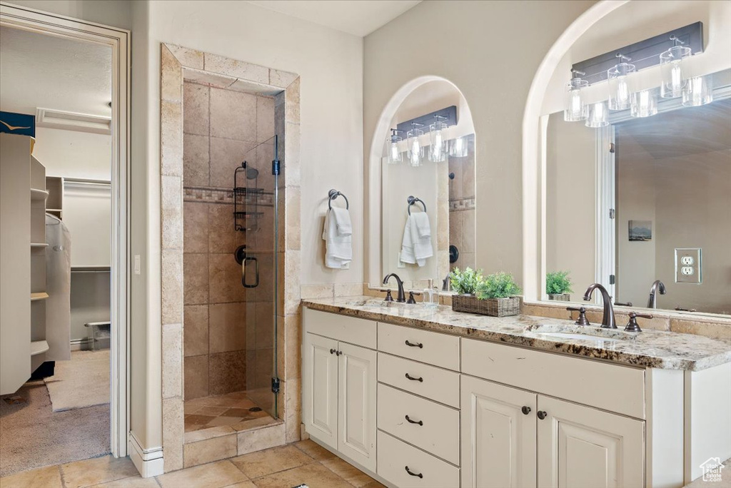 Bathroom featuring tile floors, an enclosed shower, large vanity, and double sink