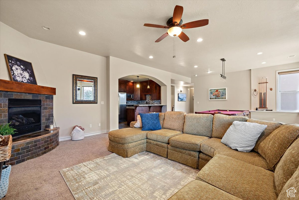 Living room with light colored carpet, pool table, ceiling fan, and a fireplace