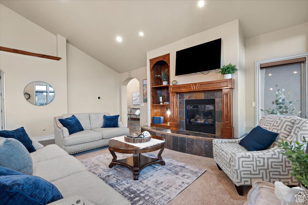 Living room with high vaulted ceiling, a tiled fireplace, and carpet flooring