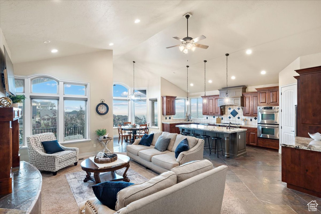 Living room with high vaulted ceiling, dark tile flooring, and ceiling fan