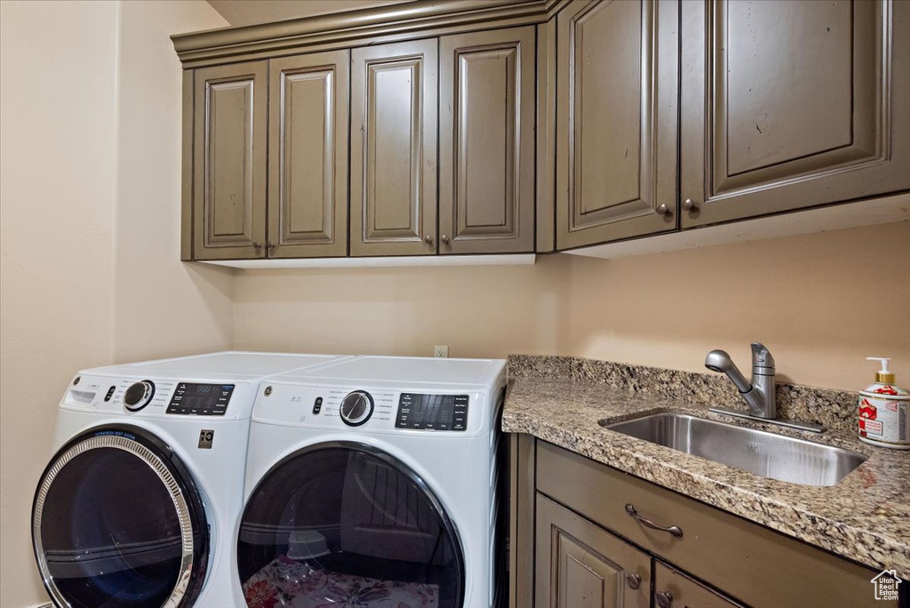 Laundry area featuring cabinets, sink, and washing machine and clothes dryer