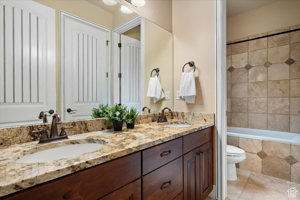 Bathroom with tile floors, toilet, and dual bowl vanity