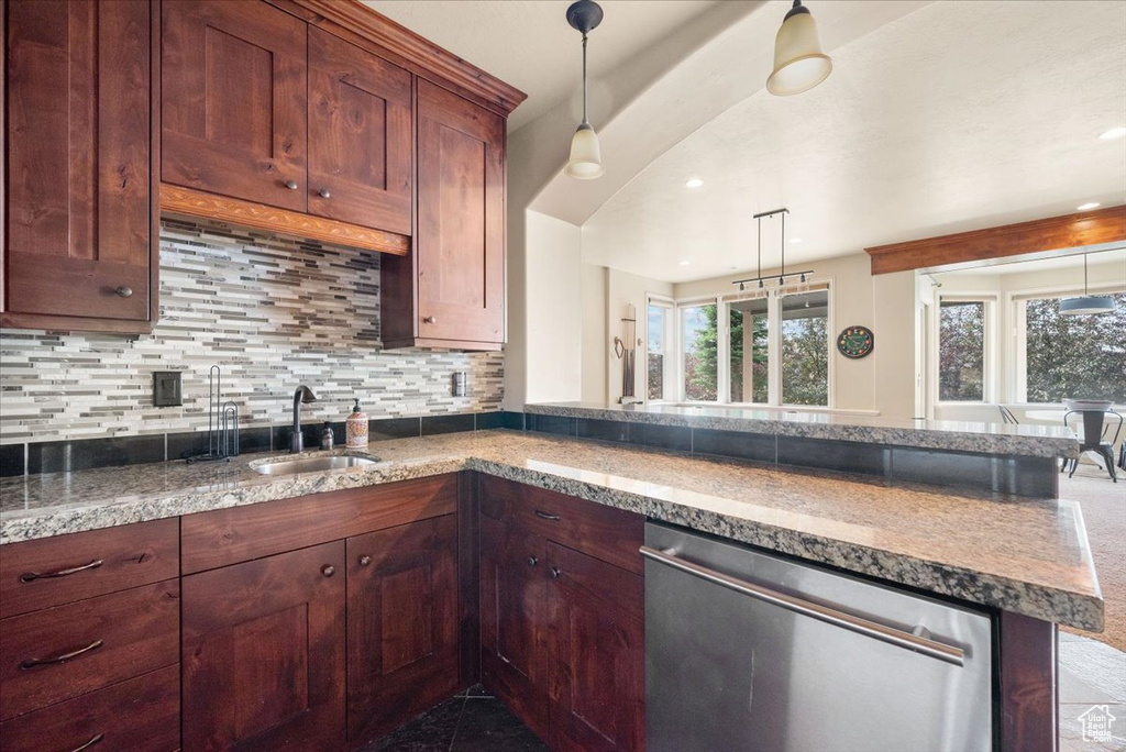 Kitchen with kitchen peninsula, dishwasher, tasteful backsplash, sink, and pendant lighting