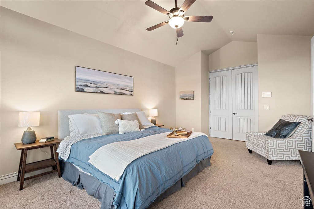 Bedroom with light carpet, a closet, ceiling fan, and vaulted ceiling