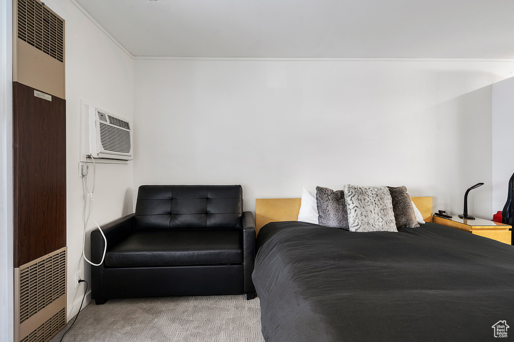 Bedroom with a wall mounted AC, ornamental molding, and carpet flooring