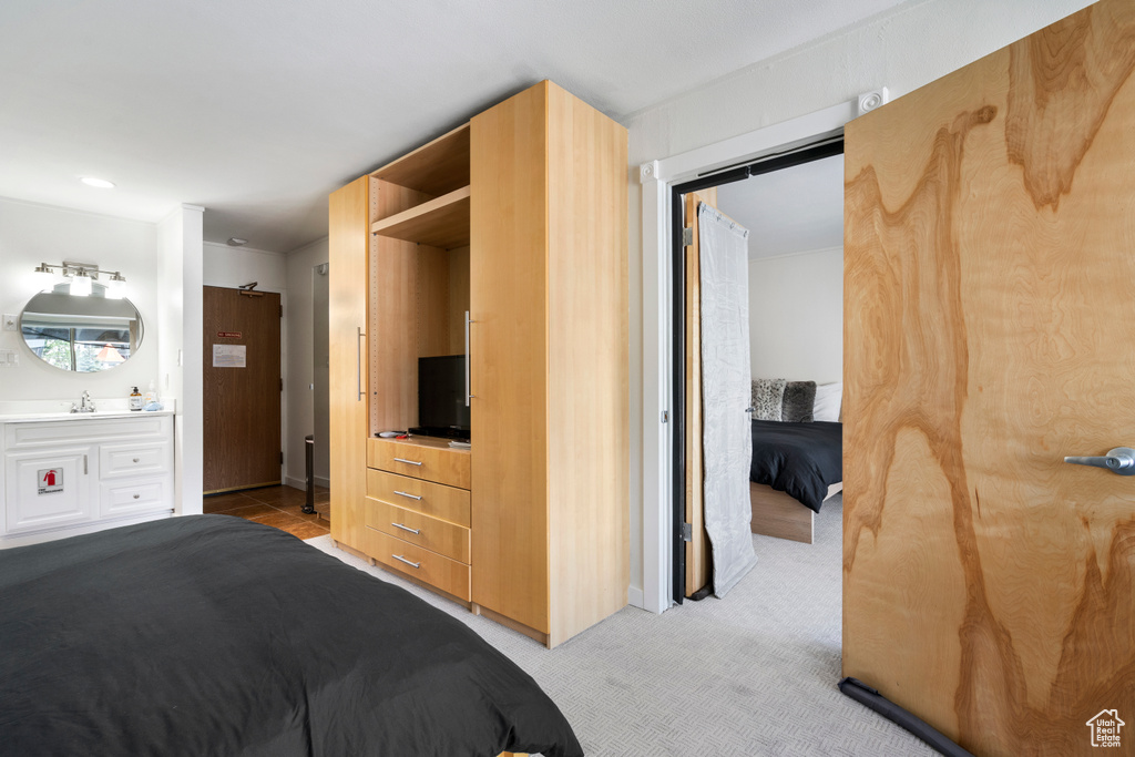 Bedroom featuring sink, ensuite bath, and light carpet