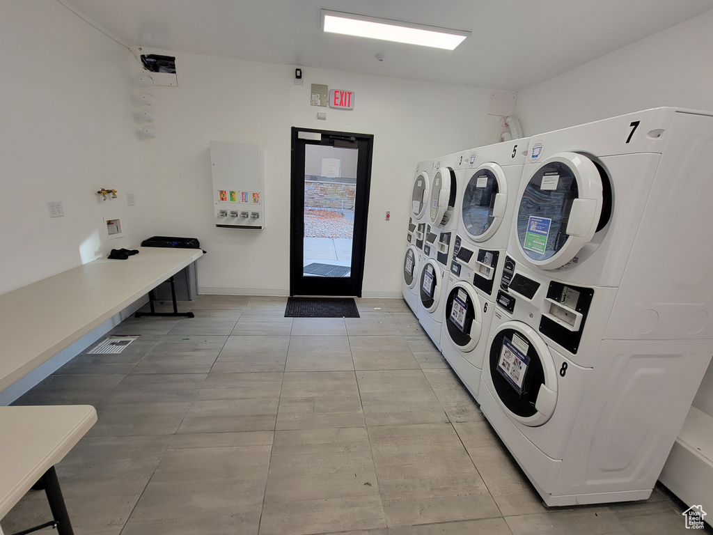 Washroom with stacked washer / dryer and light tile floors