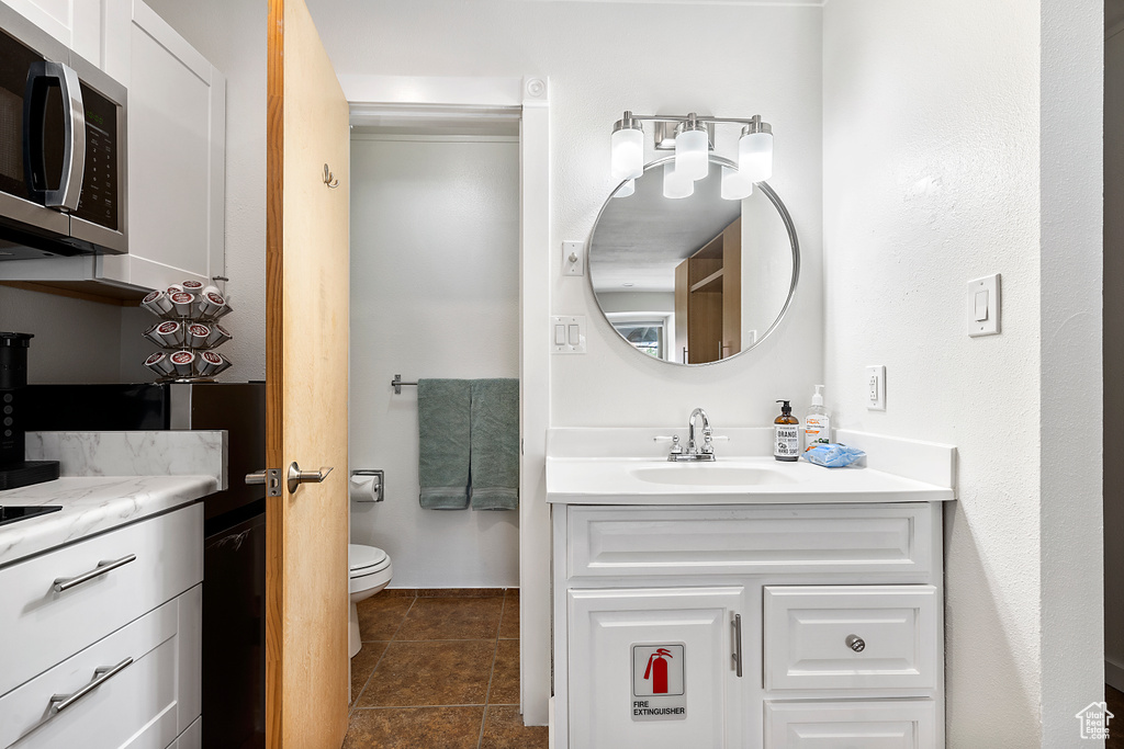 Bathroom with tile flooring, toilet, and large vanity