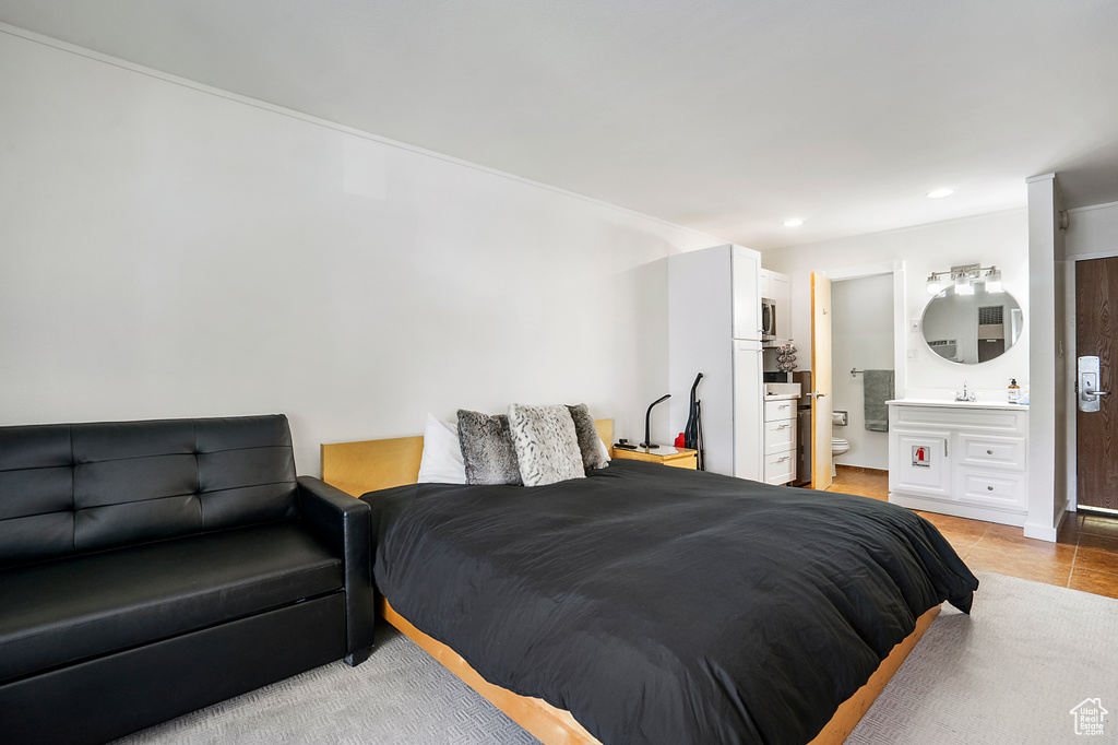 Bedroom featuring ensuite bathroom and light tile floors