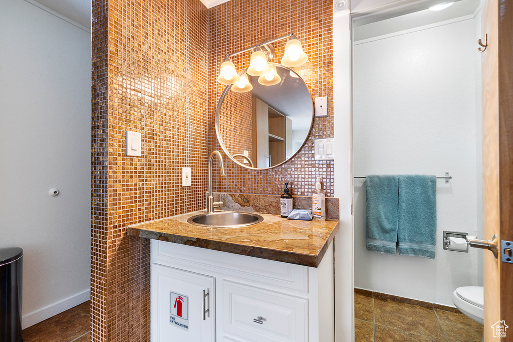 Bathroom featuring tasteful backsplash, vanity with extensive cabinet space, tile walls, tile floors, and toilet