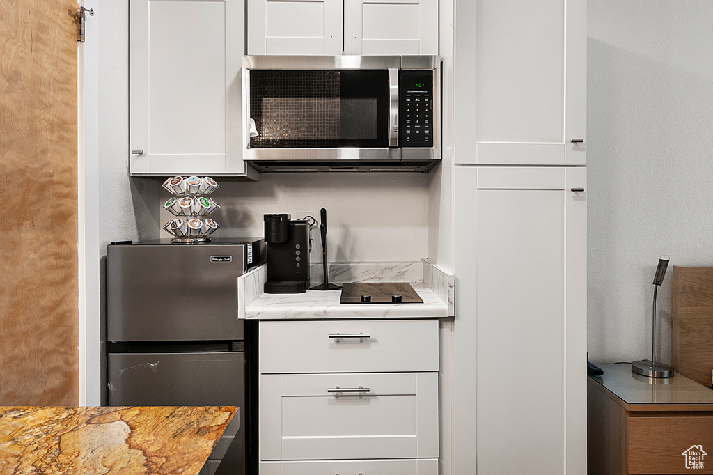 Kitchen featuring white cabinets, light stone counters, and stainless steel appliances