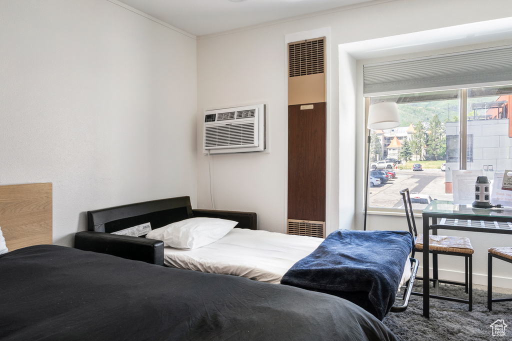 Carpeted bedroom featuring ornamental molding and a wall mounted air conditioner