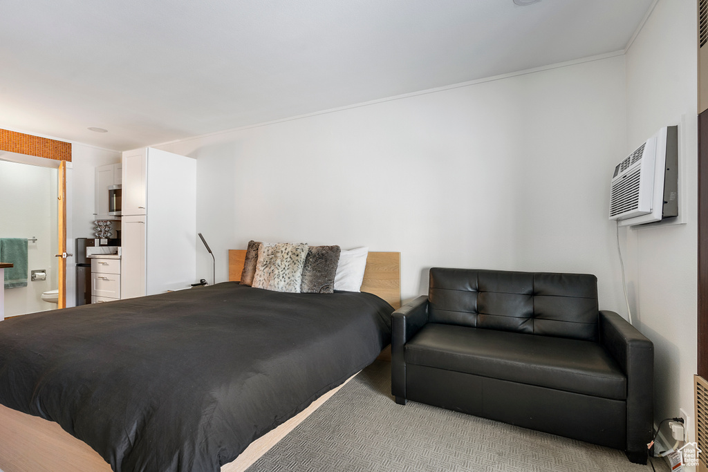 Carpeted bedroom with a wall mounted AC and connected bathroom