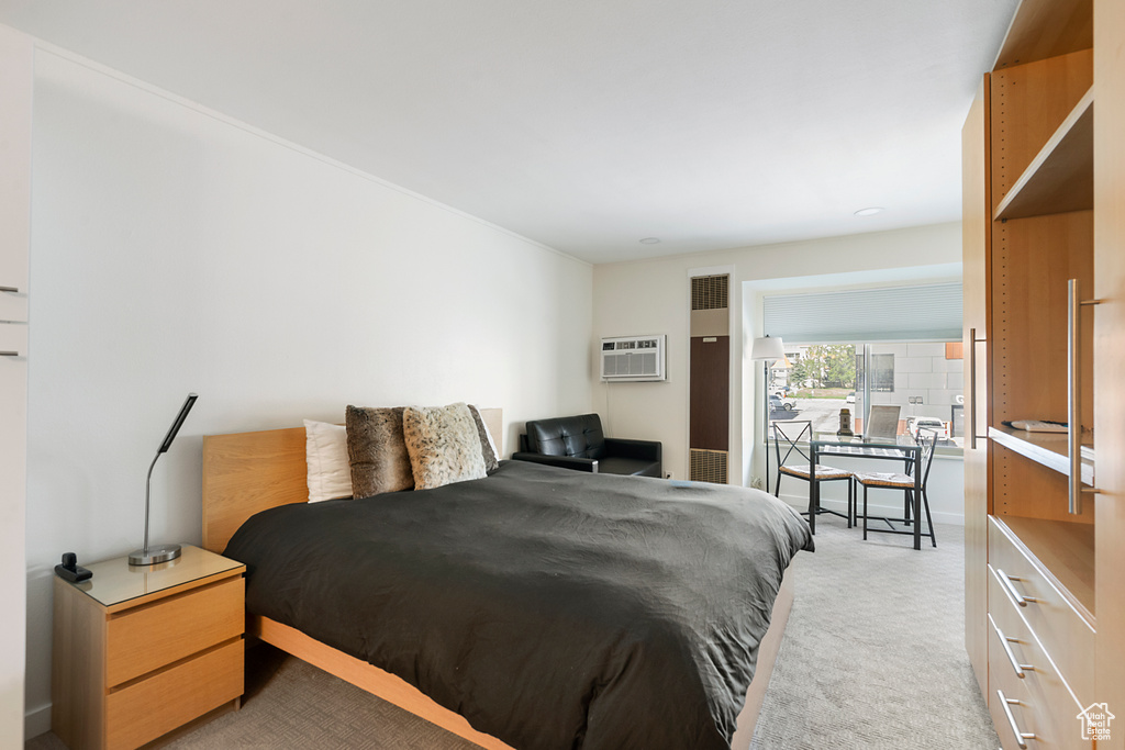 Bedroom with a wall unit AC and light carpet