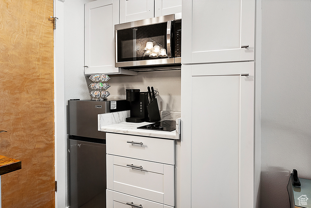 Kitchen featuring white cabinetry and light stone counters