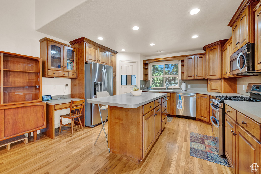 Kitchen featuring a center island, stainless steel appliances, light hardwood / wood-style floors, and a breakfast bar area