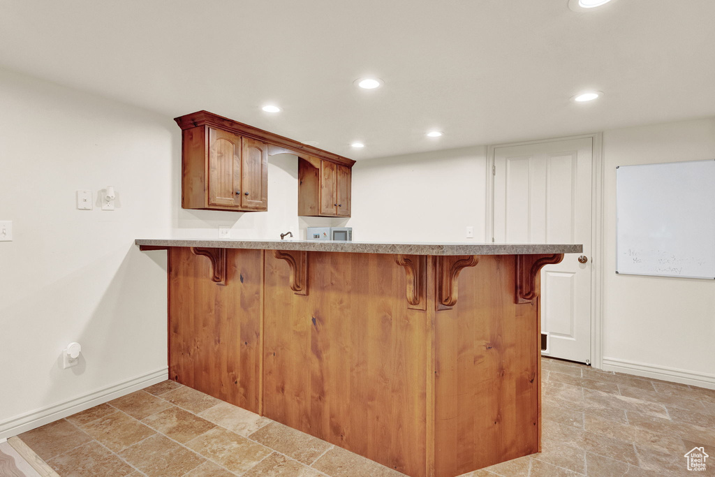 Kitchen with kitchen peninsula, light tile floors, and a breakfast bar