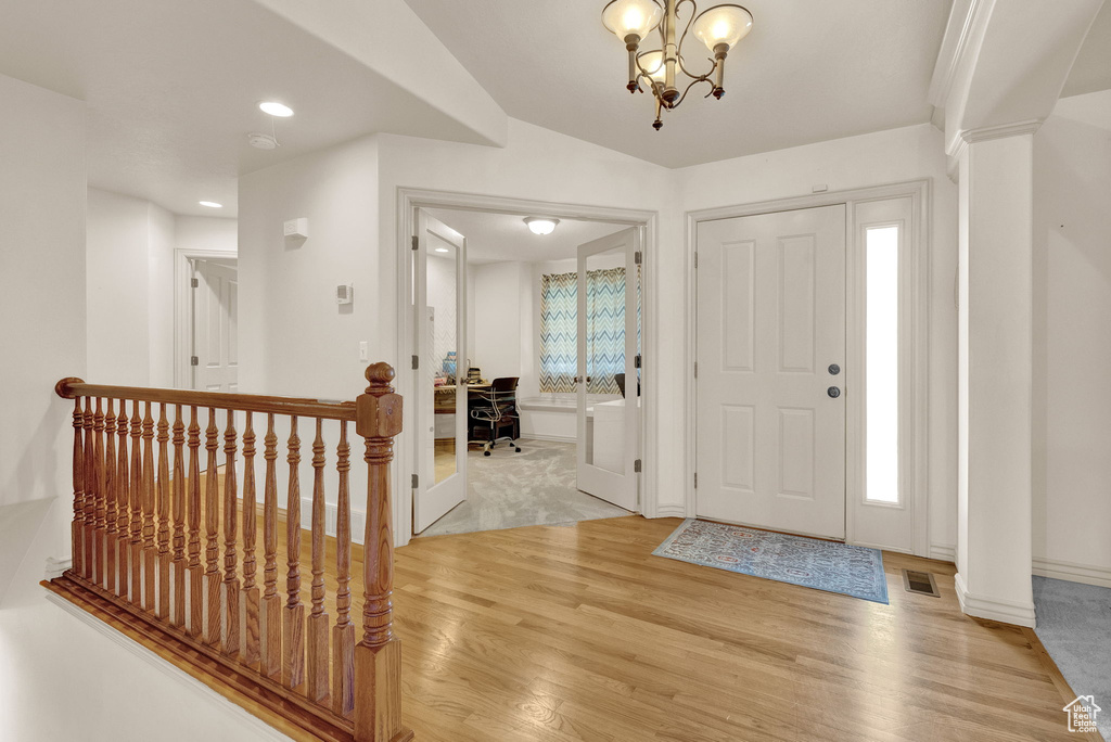 Foyer with a notable chandelier, plenty of natural light, and light wood-type flooring