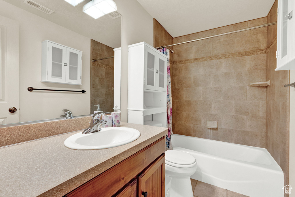 Full bathroom featuring tile flooring, vanity with extensive cabinet space, shower / tub combo with curtain, and toilet