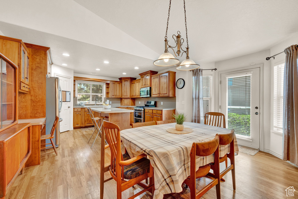 Dining space with light hardwood / wood-style flooring and lofted ceiling