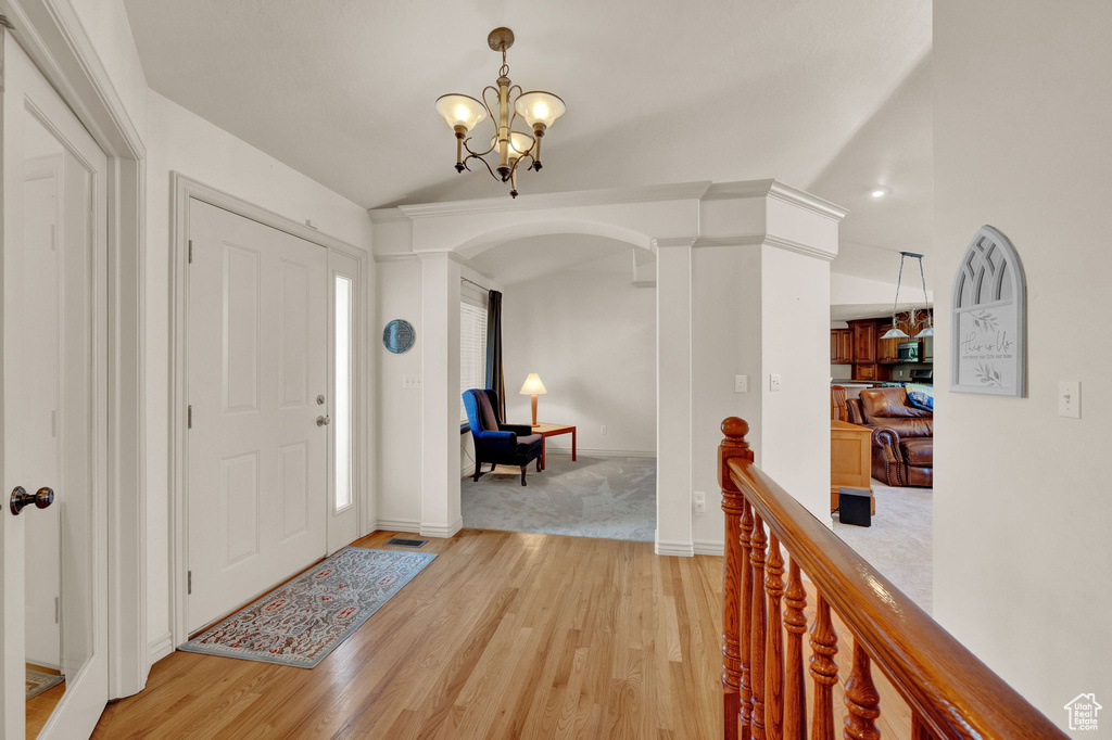 Entryway featuring light hardwood / wood-style floors, decorative columns, and a chandelier