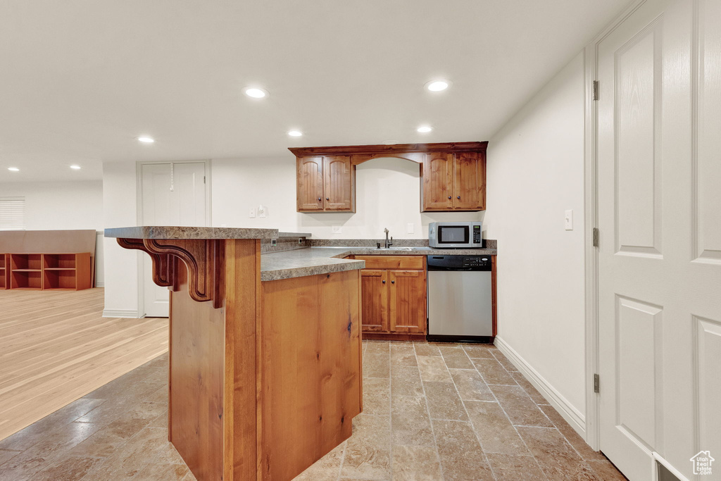 Kitchen featuring appliances with stainless steel finishes, sink, light tile flooring, and a breakfast bar