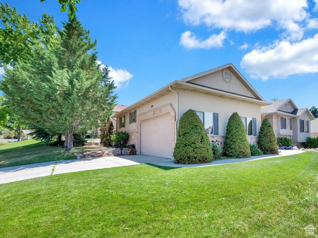 View of front of property featuring a garage and a front lawn